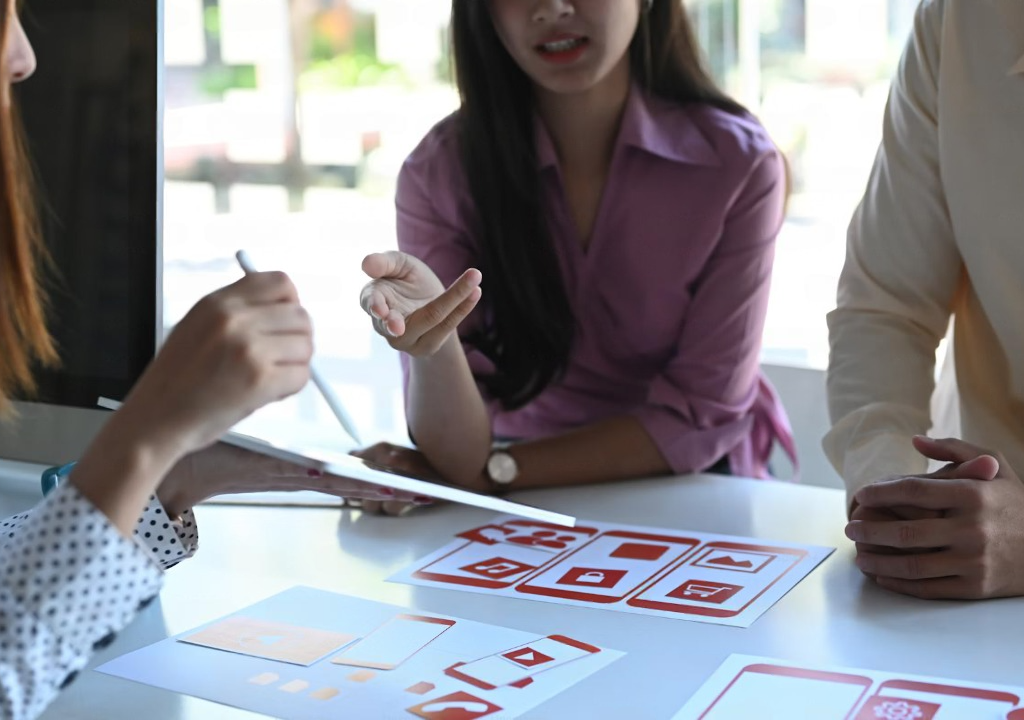 Business and software strategy team discussing project plans around a table, illustrating offshore software development as a strategic imperative in 2026 for scalability, faster delivery, and access to global tech talent.