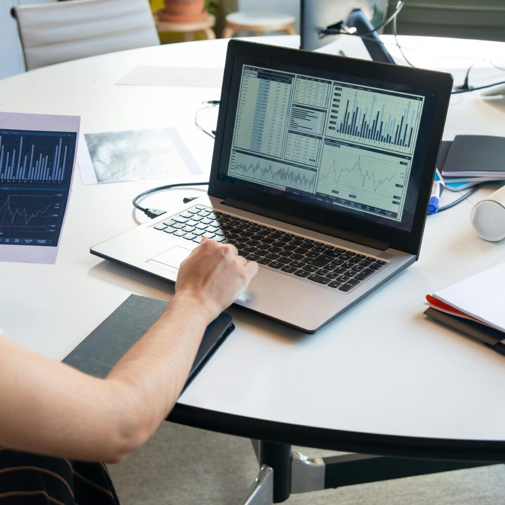 Laptop displaying cost analysis charts and performance metrics on a desk, illustrating offshore software development cost savings, pricing comparison, and financial ROI beyond hourly rates.
